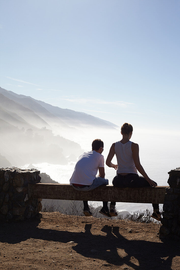 Young couple looks at coastal panorama in the fog. Highway 1, California, USA