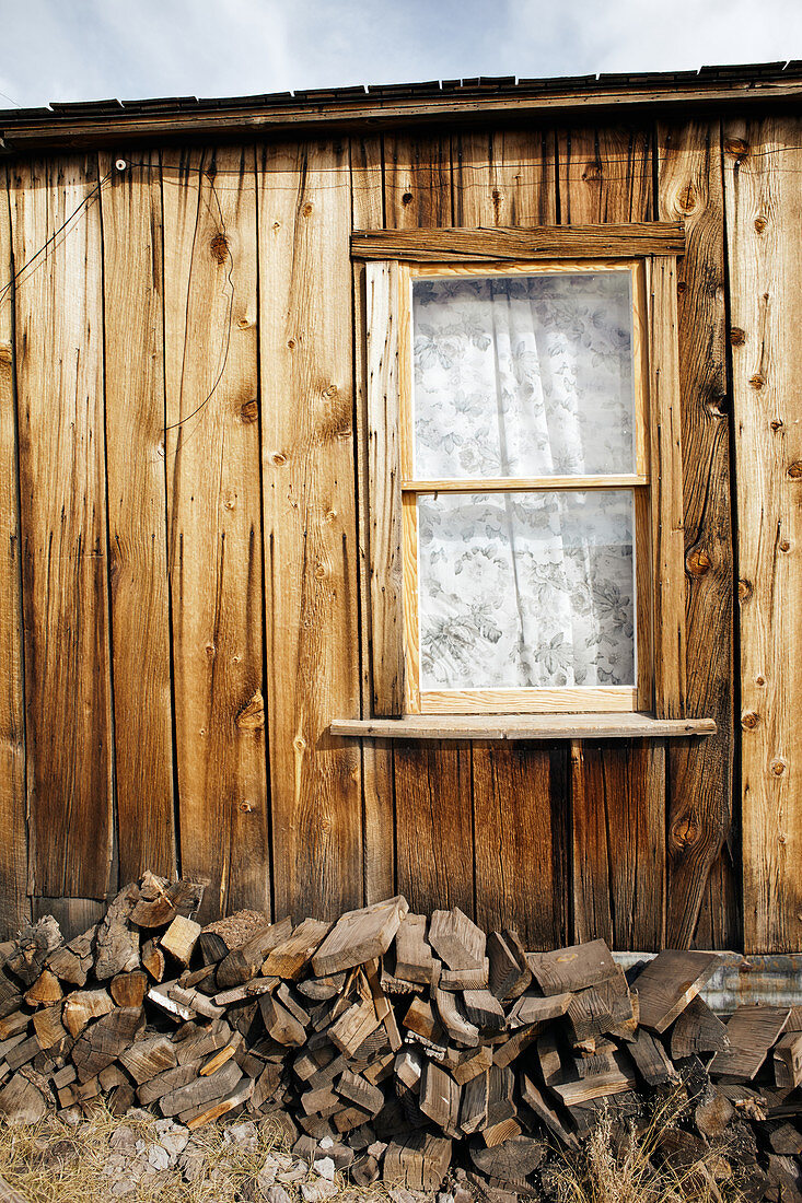 Hausseite mit Fenster und Feuerholz in der Geisterstadt Bodie, Eastern Sierra, Kalifornien, USA