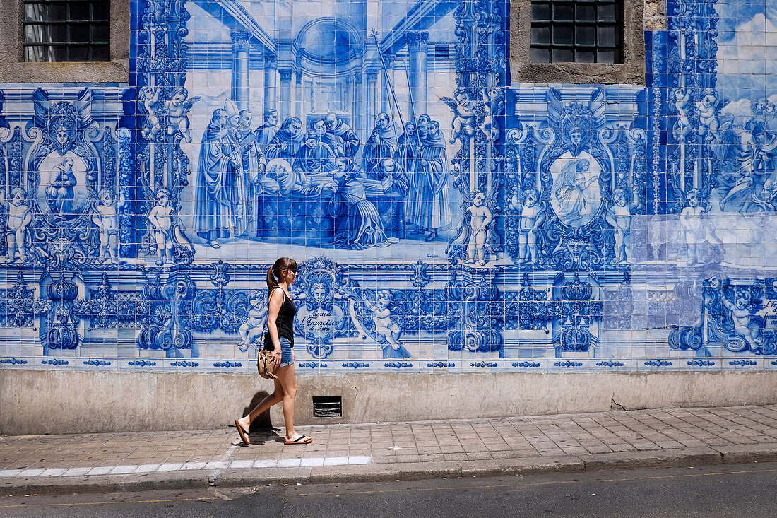 Tourist in Porto in front of blue mural in the street, Portugal