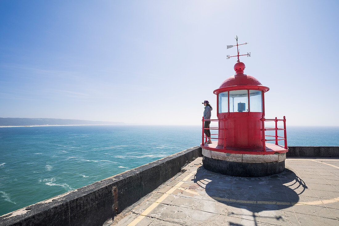 Frau mit Blick aufs Meer am Leuchtturm Nazare, Portugal\n