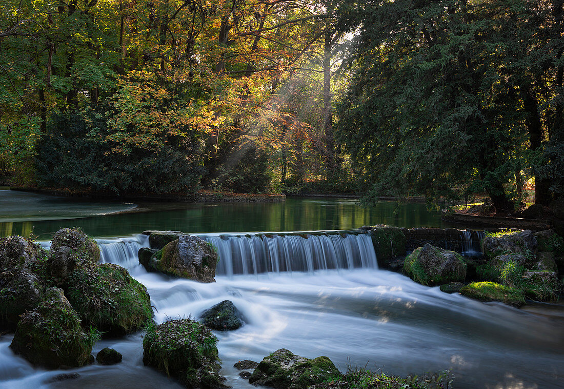 Wasserfall am Schwabinger Bach im Englischen Garten im Herbst am Nachmittag in München, Bayern\n