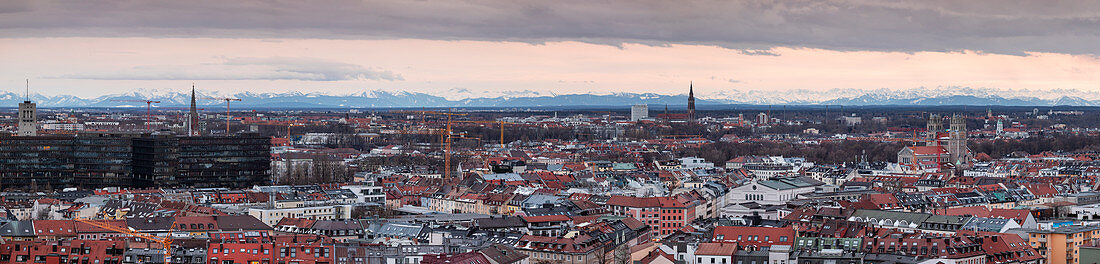 Panoramic skyline of Munich city with snowy Alps in the background at sunset