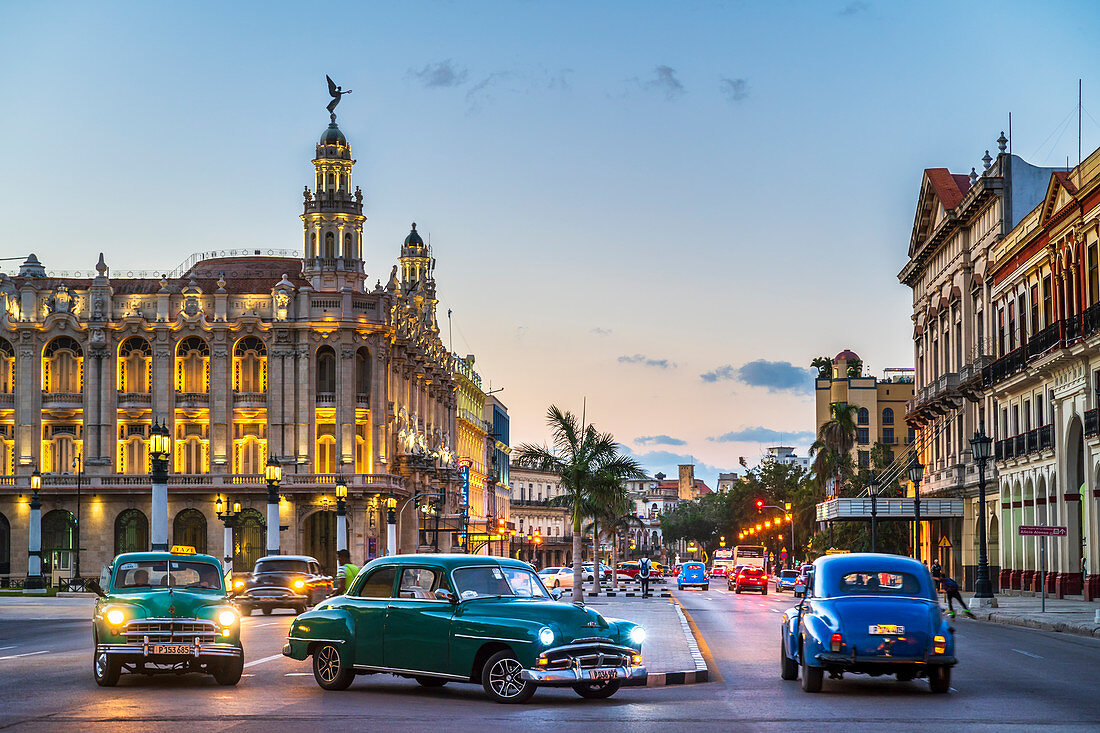 Vintage American cars turning and The Gran Teatro de La Habana at dusk, UNESCO, Havana, Cuba, West Indies, Caribbean, Central America