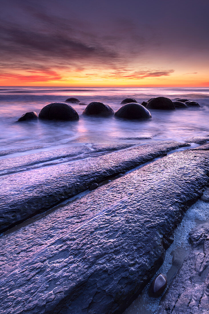 Die Moeraki Boulders mit dramatischem Sonnenaufgang am Moeraki Beach, Otago, Südinsel, Neuseeland, Pazifik