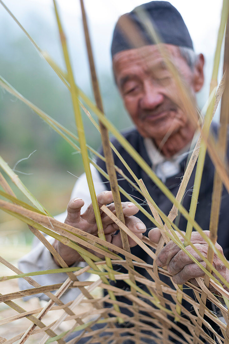 Ein alter nepalesischer Mann webt aus Bambus einen traditionellen Korb, Kathmandu-Tal, Nepal, Asien
