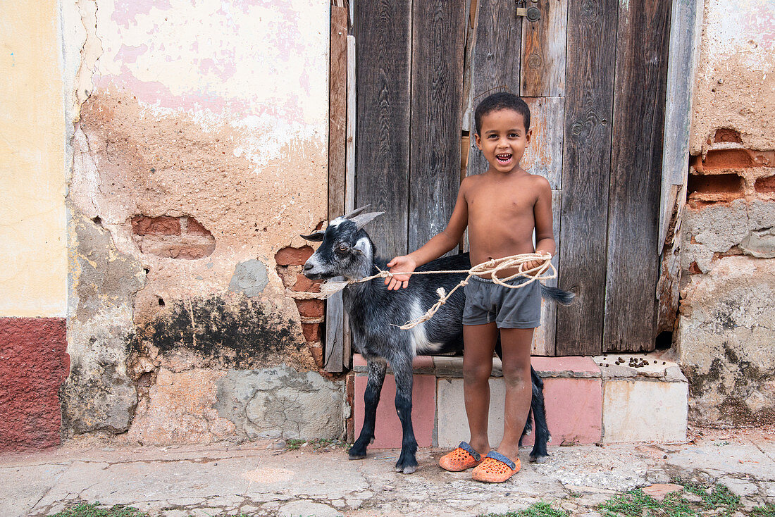 Einheimischer Junge mit seiner Ziege auf einer Stadtstraße in Trinidad, Kuba, Westindien, Karibik, Mittelamerika