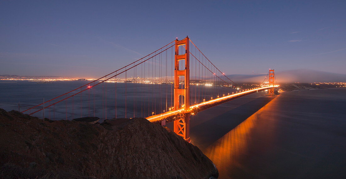 Die Golden Gate Bridge leuchtet bei Sonnenuntergang mit der Skyline von San Francisco im Hintergrund, gesehen von den Marin Headlands, San Francisco, Kalifornien, Vereinigte Staaten von Amerika, Nordamerika