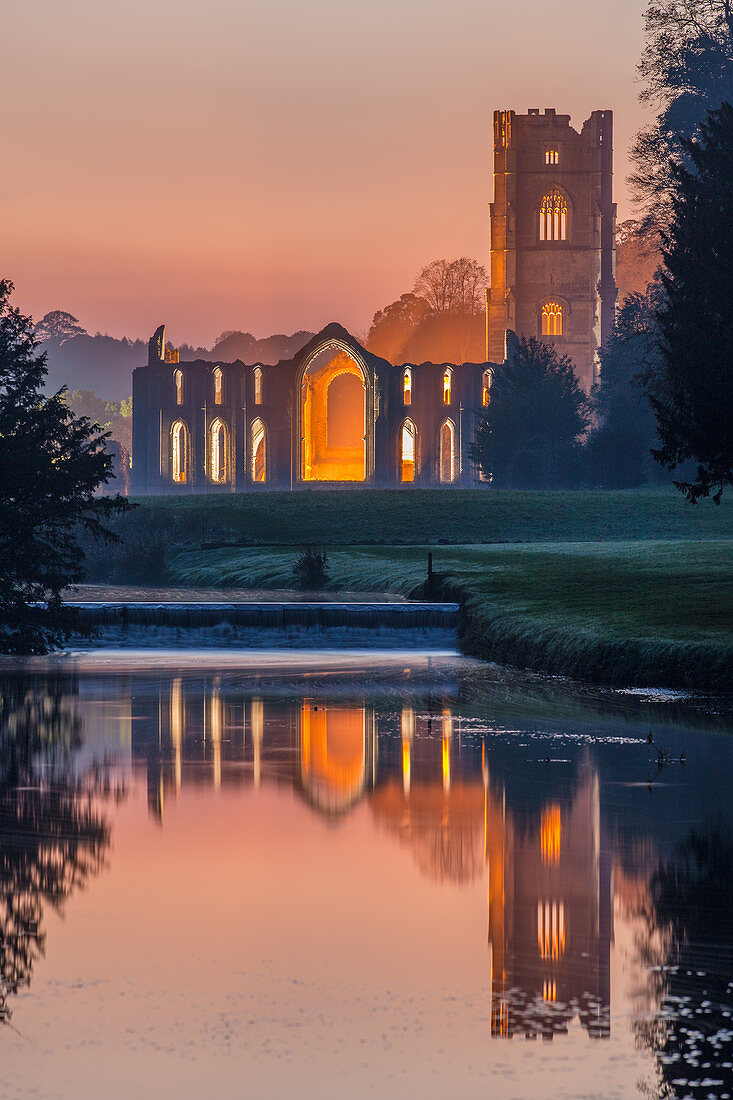 Das Zisterzienserkloster von Fountains Abbey in der Abenddämmerung spiegelte sich im Fluss Skell, UNESCO-Weltkulturerbe, North Yorkshire, Yorkshire, England, Vereinigtes Königreich, Europa