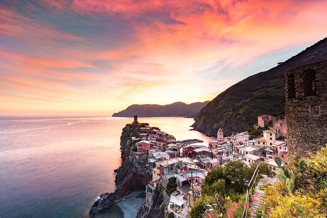 The setting sun lights up the sky and casts an orange glow over the old town and harbour of Vernazza, Cinque Terre, UNESCO World Heritage Site, Liguria, Italy, Europe
