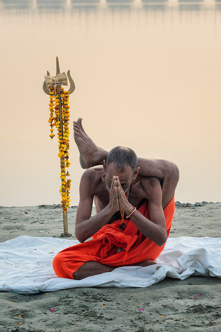 Sadhu practising yoga at sunrise on Ganges riverbank, Allahabad Kumbh Mela, Allahabad, Uttar Pradesh, India, Asia