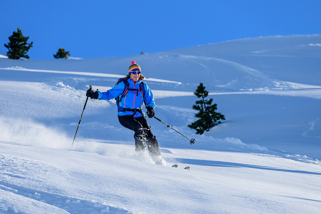 Frau auf Skitour fährt durch Pulverschnee ab, Regenfeldjoch, Kitzbüheler Alpen, Tirol, Österreich