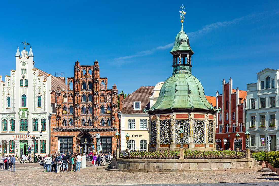 Marktplatz (market place square) in the centrum of Wismar, Brick Gothic Bürgerhaus (patrician's home) called the Alter Schwede (The Old Swede), erected around 1380. "Wasserkunst", historic ornate structure on the site of a 16th-century water fountain designed by Philipp Brandin. Wismar stadt, Mecklenburg–Vorpommern, Germany.