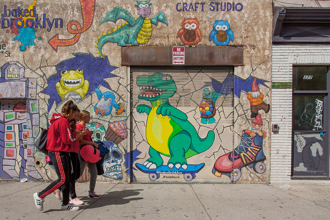 Mädchen vor einer mit Graffiti bemalten Wand auf der Straße, Brooklyn, New York City, New York, Vereinigte Staaten, USA