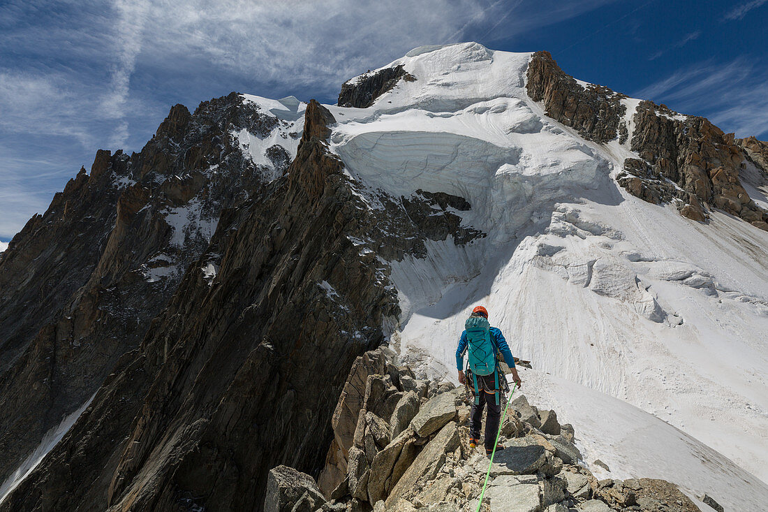 MOUNTAINEER FOLLOWING THE ROCKY CREST OF THE LACHENAL POINTS AT THE FOOT OF THE SERACS OF THE MONT-BLANC DU TACUL, MASSIF OF THE MONT-BLANC, CHAMONIX-MONT-BLANC, HAUTE-SAVOIE (74), FRANCE