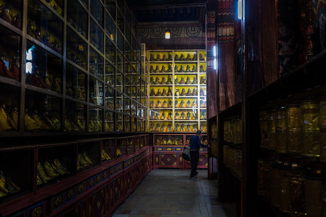 Besucher beim Betrieb von Gebetsmühlen umgeben von Statuetten buddhistischer Gottheiten im Tempel der Stadt Ulan-Bator, Mongolei