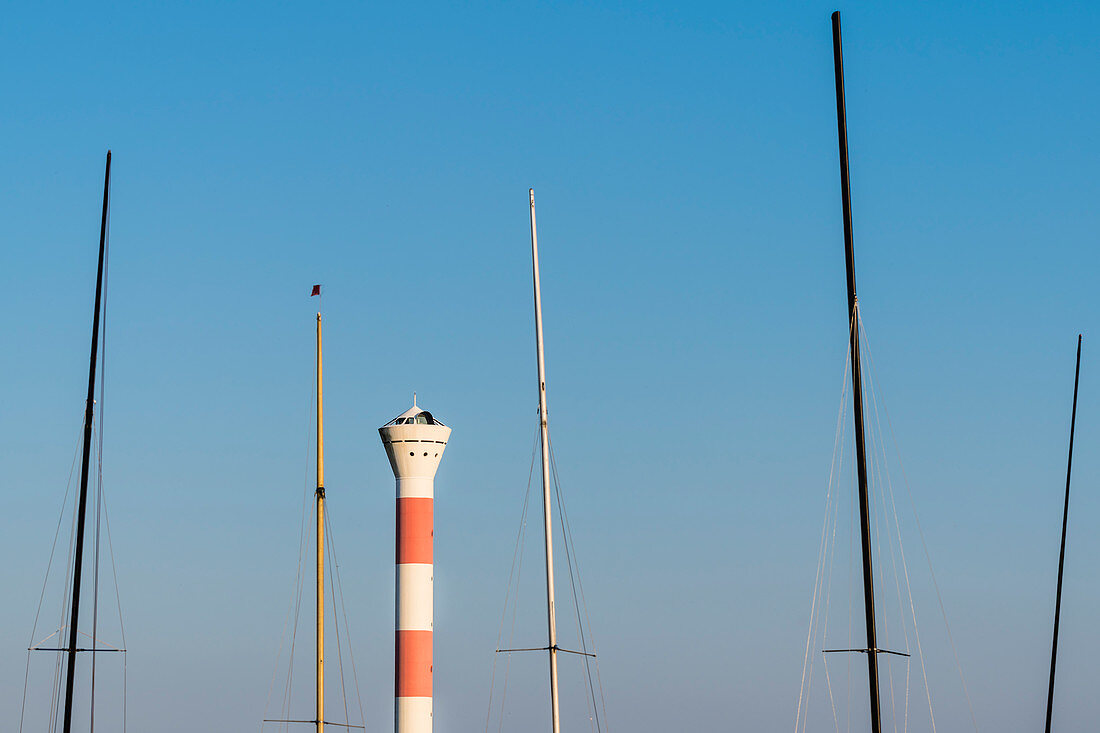 Ein Leuchtturm an der Elbe, eingerahmt von den Masten einiger Segelschiffe, Blankenese, Hamburg, Deutschland