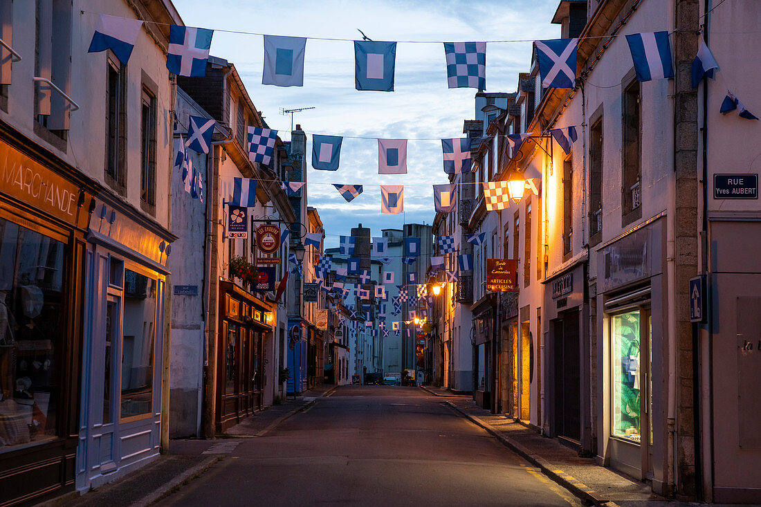 Rue Dumont d'Urville with blue and white flags at dusk, Concarneau, Arrondissement Quimper, Departement Finistere, Brittany, France, Europe