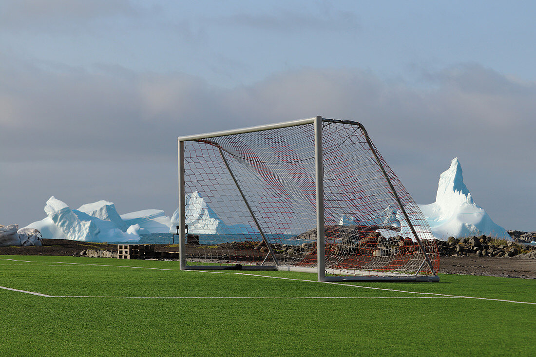 Fußballplatz mit Tor direkt am Meer, Ortsrand von Qeqertarsuaq, im Hintergrund Eisberge, Diskoinsel in Westgrönland, Grönland