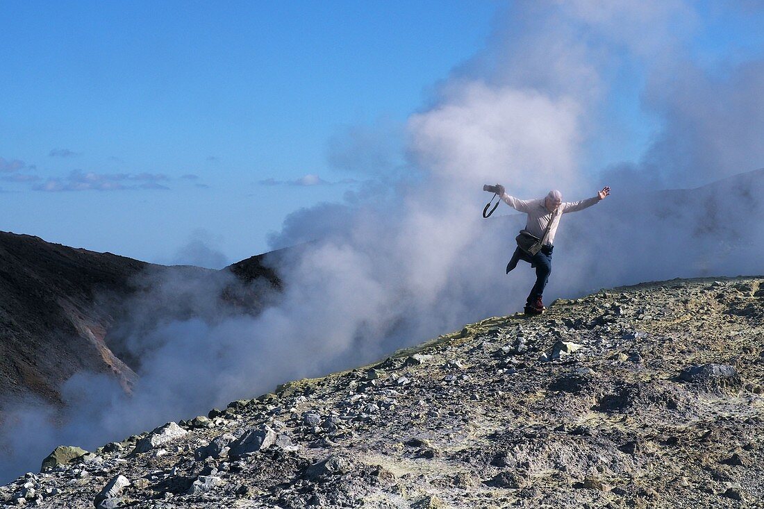 Mann kommt aus dem Vulkandampf am Kraterrand auf dem Vulkan, Insel Vulkano, Liparische Inseln, Süd- Italien