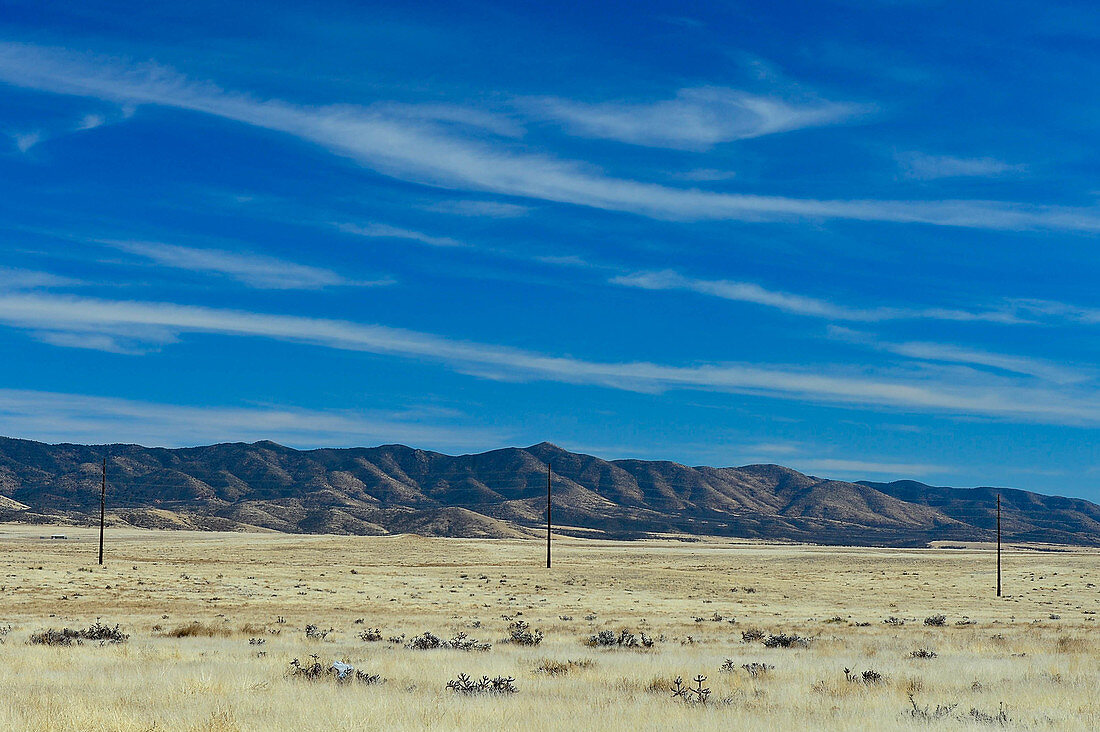 Eine Telegrafenleitung vor einer Hügelkette in der weiten Landschaft, nahe Sedona, Arizona, USA