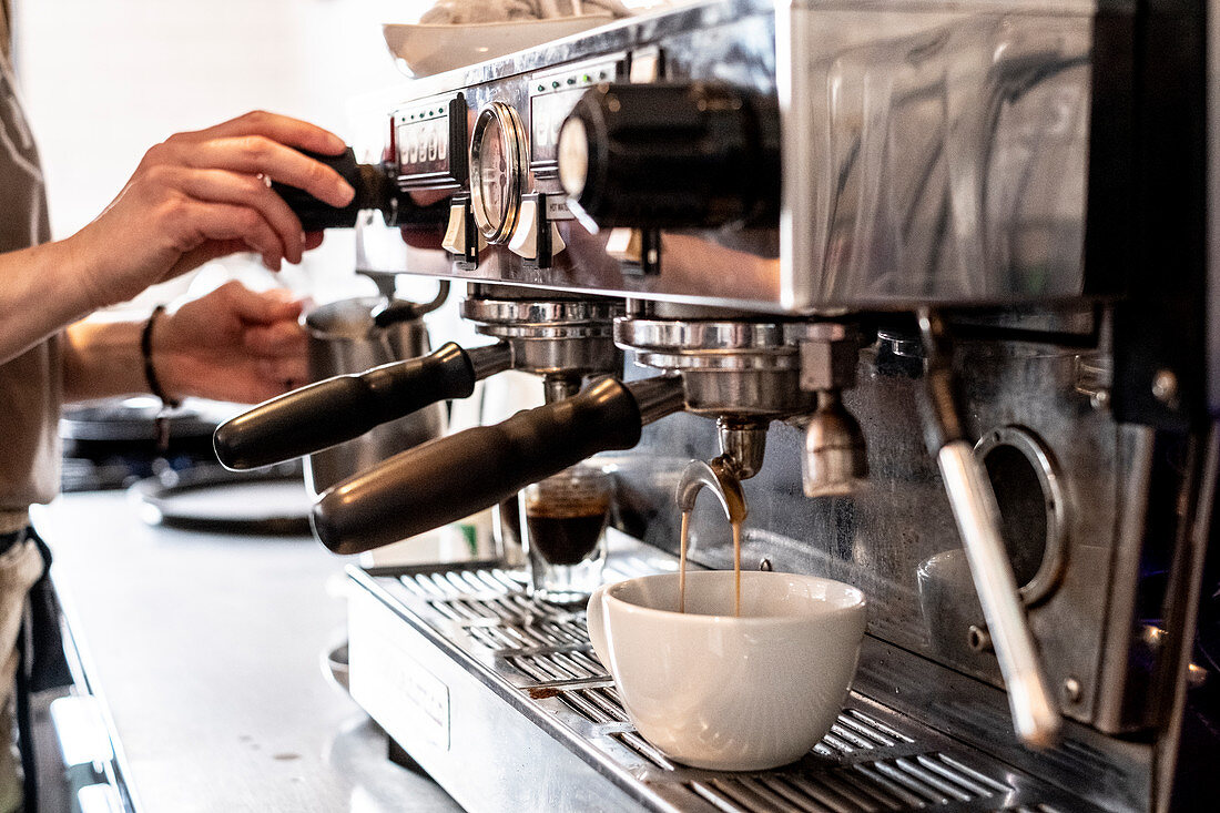 Close up of person making a cappuccino using commercial espresso machine.
