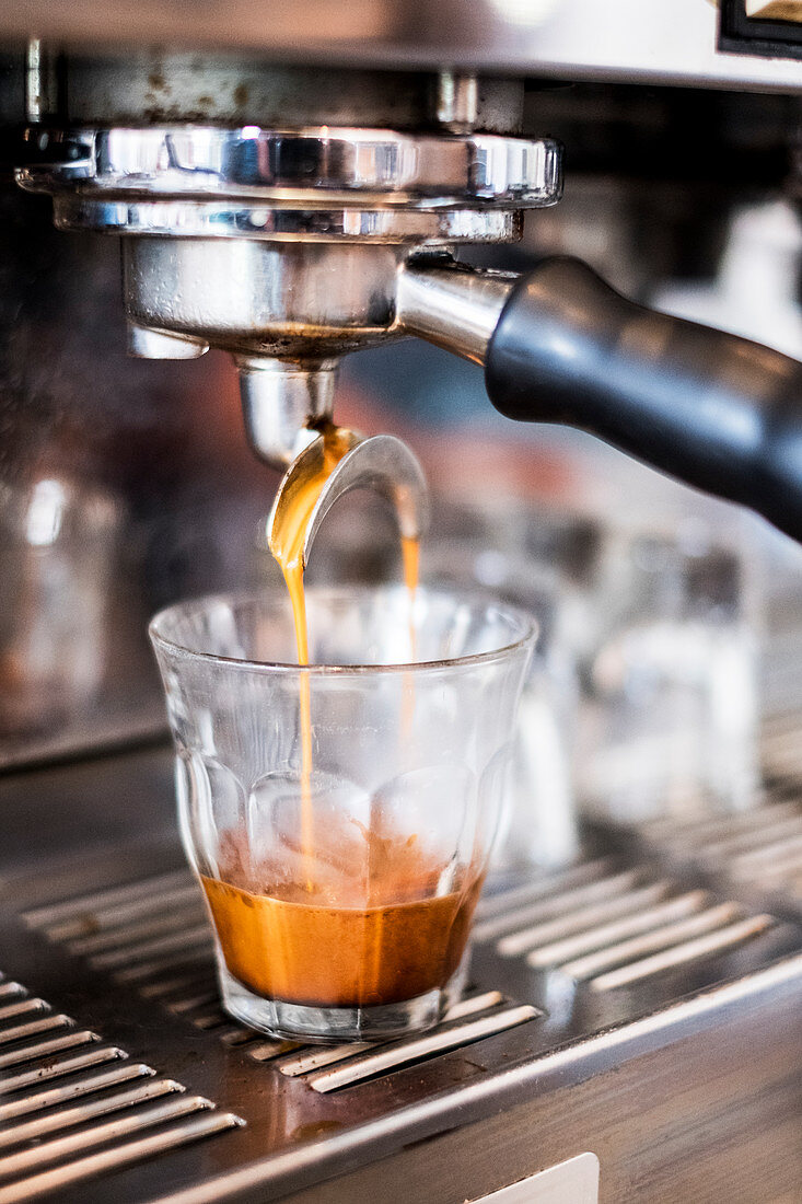 A commercial expresso machine in a coffee shop making an expresso shot.