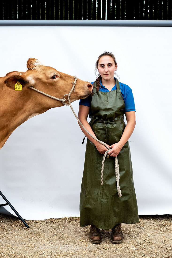 Portrait of female farmer wearing green apron with a Guernsey cow.