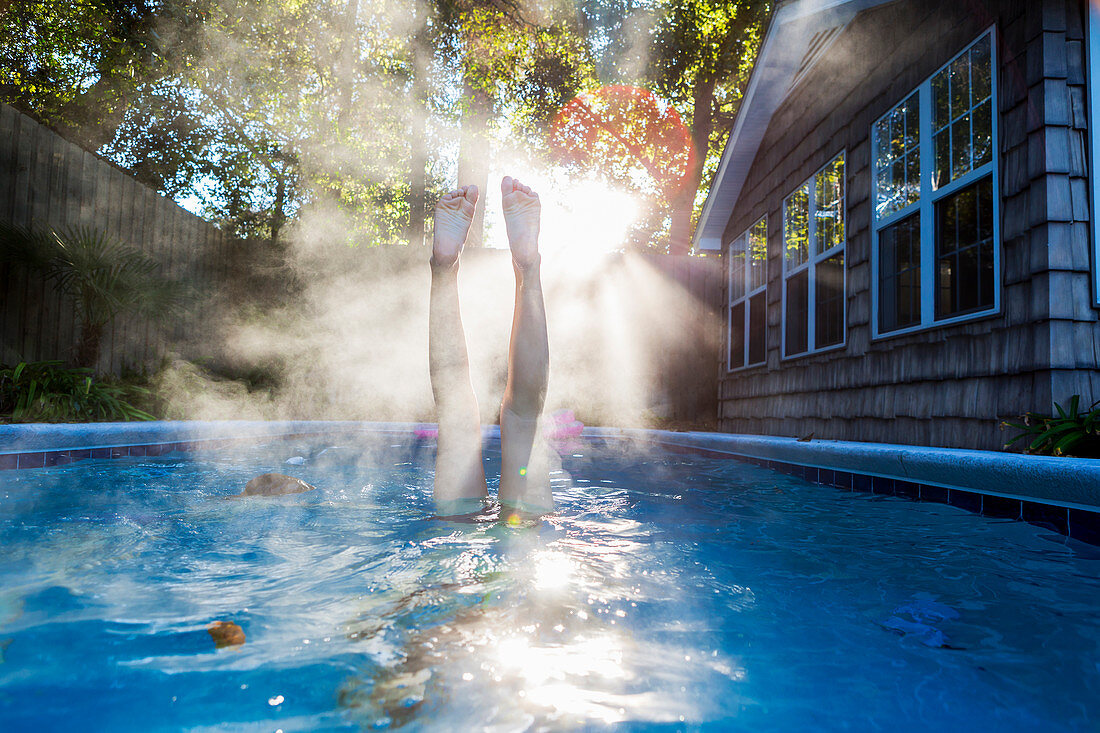 Teenager-Mädchen schwimmt in einem Pool, taucht in warmes Wasser, Dampf steigt auf