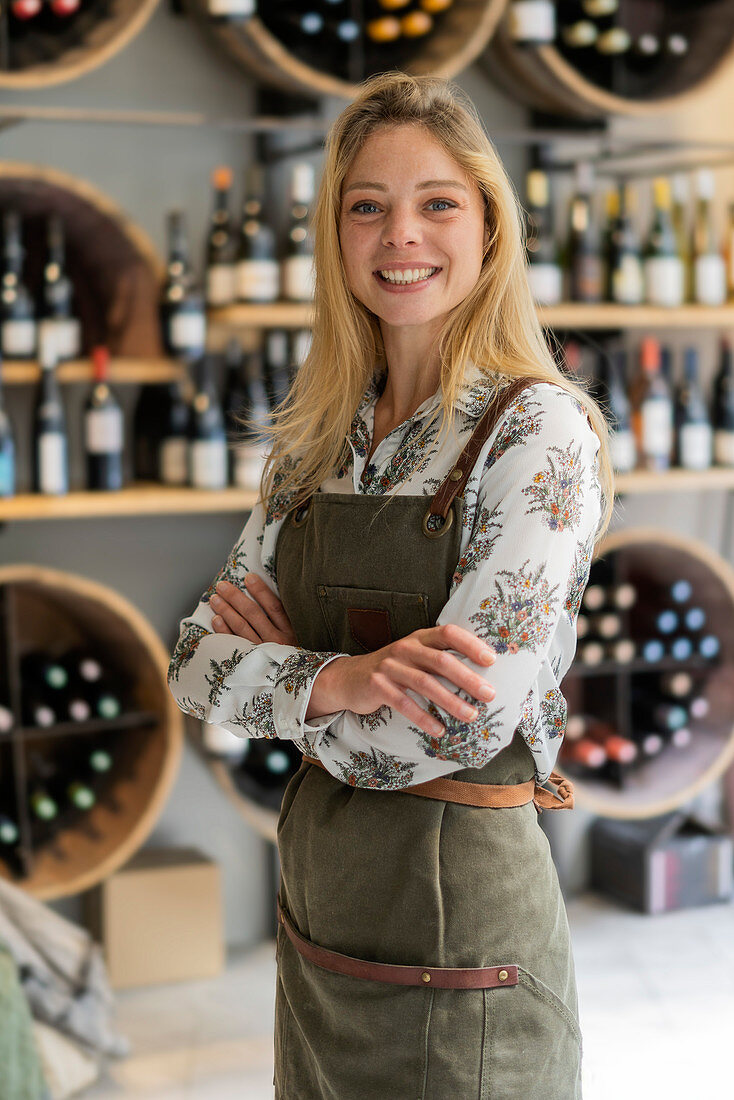 Young woman wearing apron standing in wine shop