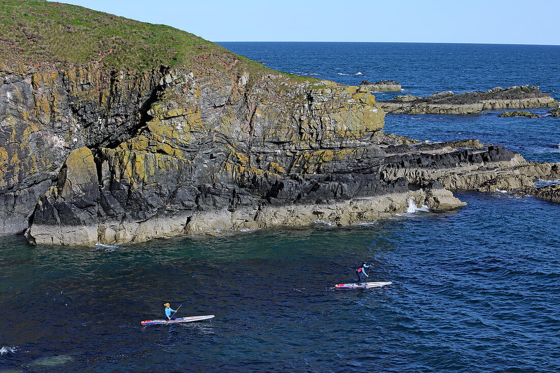 Stand-up paddler on the coast at Whinnyfold, Aberdeenshire
