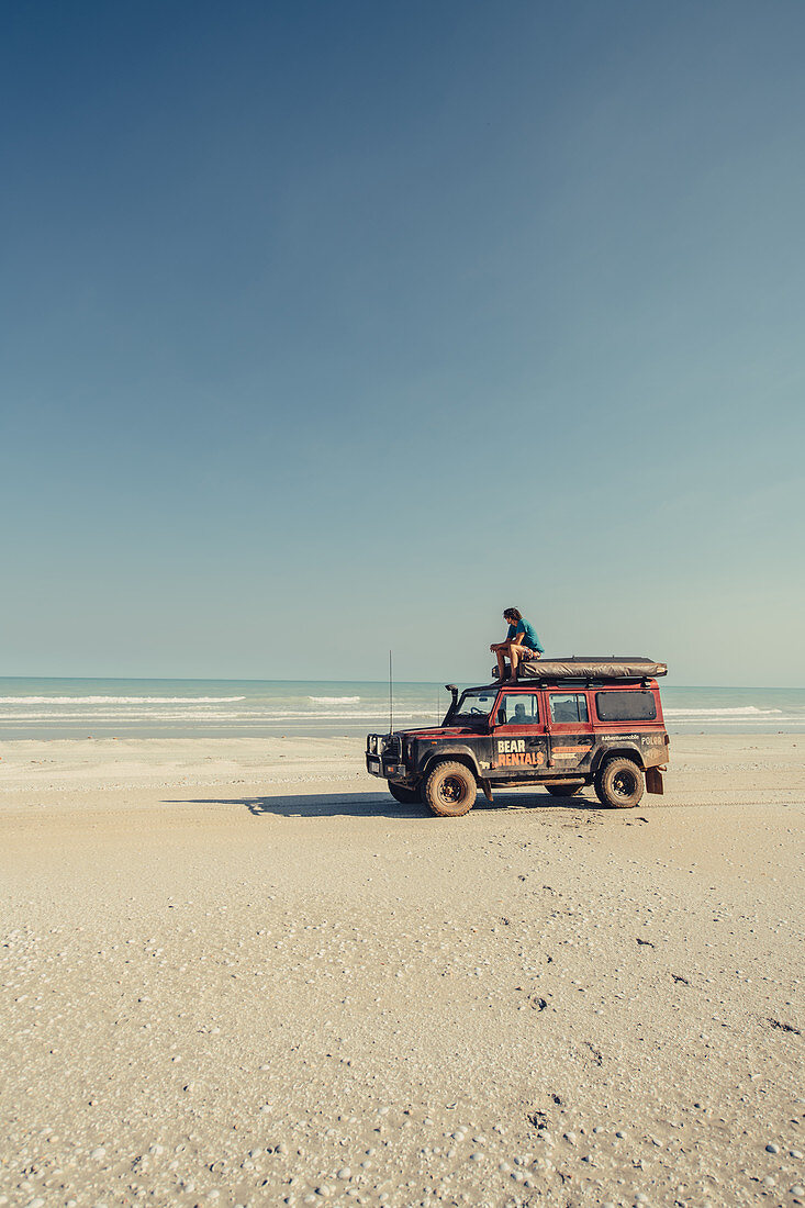 Mann sitzt auf Geländewagen am 80 Mile Beach in Westaustralien, Australien, Indischer Ozean, Ozeanien
