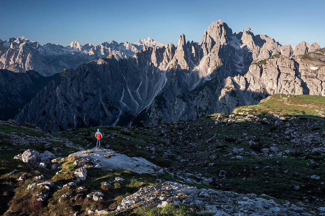 Mann in Berglandschaft in den Dolomiten unterhalb der Lavardo Hütte nähe Drei Zinnen im Sonnenaufgang, Südtirol