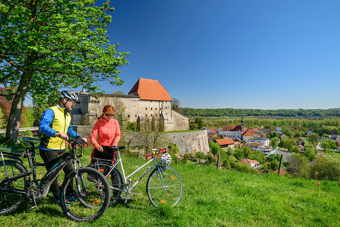 Frau und Mann beim Radfahren machen vor Burg Tittmoning Pause, Tittmoning, Benediktradweg, Oberbayern, Bayern, Deutschland