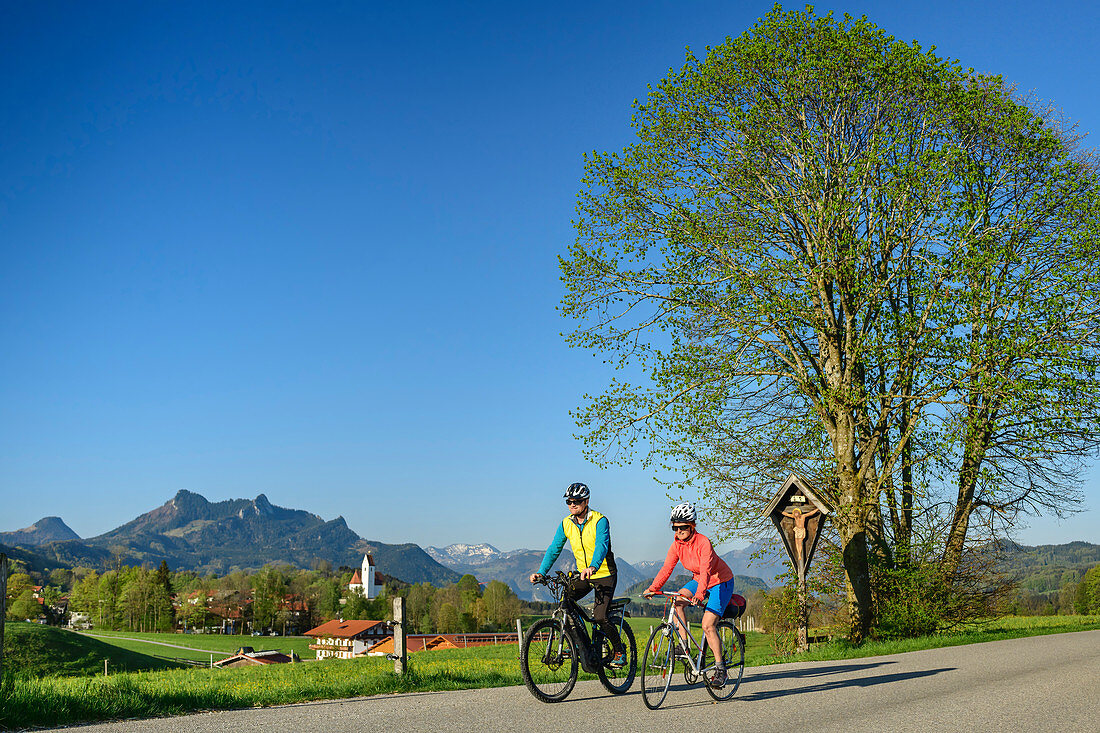 Frau und Mann beim Radfahren, Grainbach und Heuberg im Hintergrund, Samerberg, Chiemgau, Chiemgauer Alpen, Oberbayern, Bayern, Deutschland