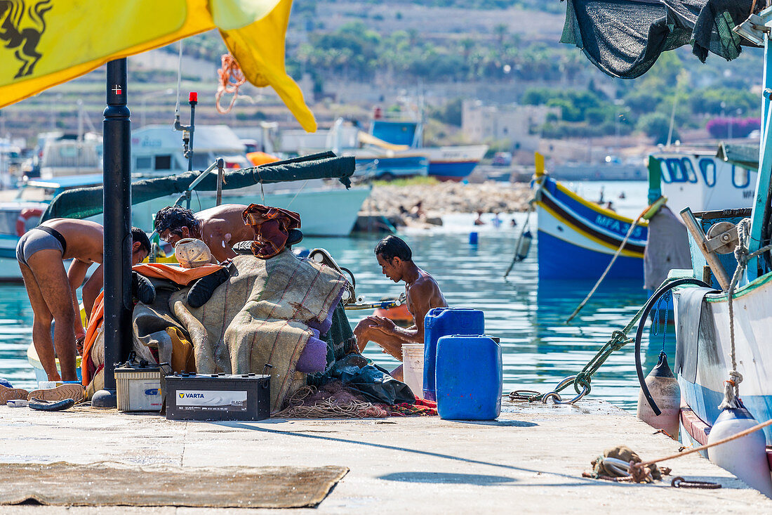 Fischer waschen sich am Hafen von Marsaxlokk, Malta