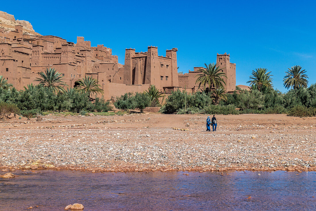 Two local women walk in front of the city of Ait Ben Haddou, Morocco