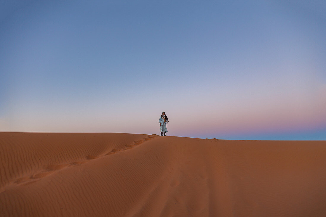 Berber steht frühmorgens auf einer Düne in der Erg Chebbi Wüste in der Sahara, Marokko