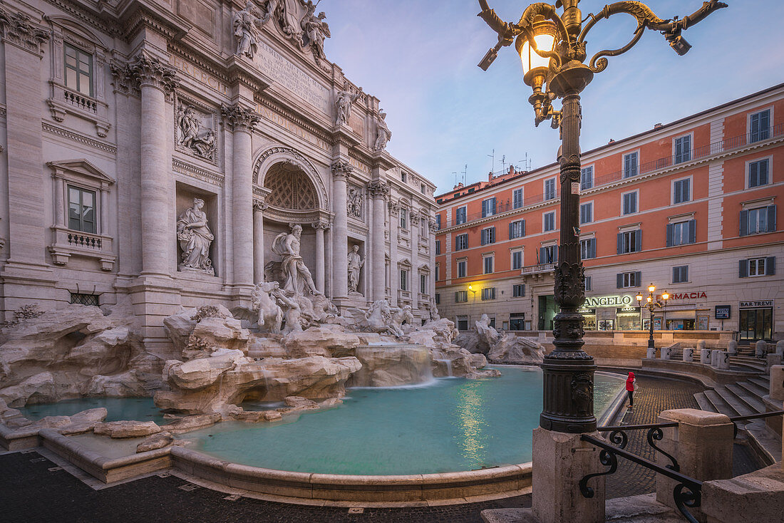 Tourist stands in front of the Trevi Fontana in Rome, Italy early in the morning