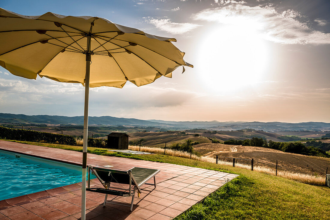 Sunbed and umbrella by a pool, Buonconvento, Tuscany, Italy