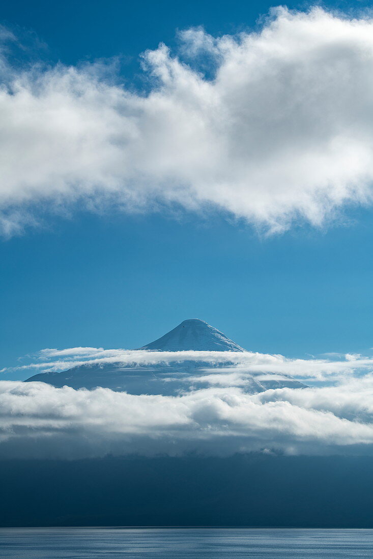 The cone of the majestic volcano Osorno on Lake Llanquihue rises above thin clouds, near Puerto Montt, Los Lagos, Patagonia, Chile, South America