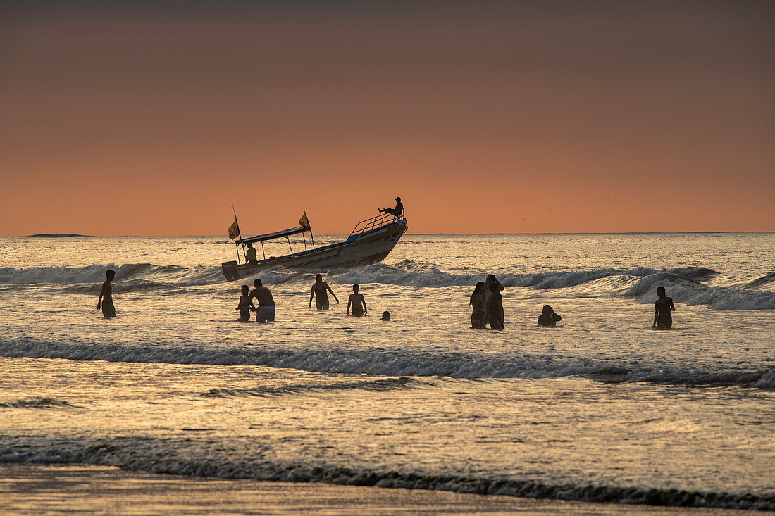 Fischer, die hüfthoch im Wasser sind, arbeiten mit einem kleinen Boot zusammen, um ihr Netz zu verbreiten, Manta, Manabi, Ecuador, Südamerika