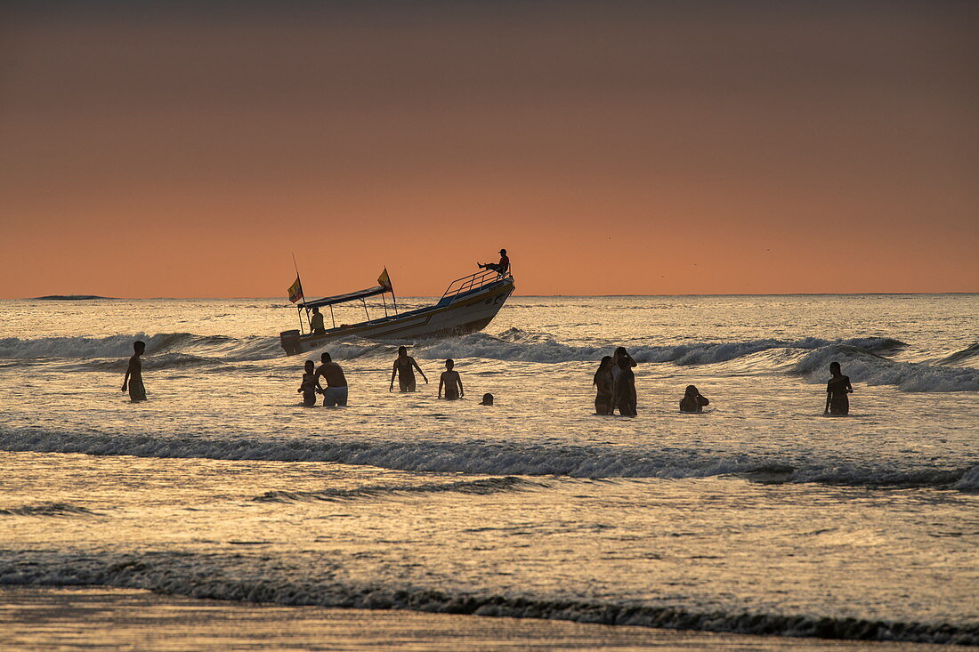 Fishermen waist-deep in the water work with a small boat to spread their net, Manta, Manabi, Ecuador, South America