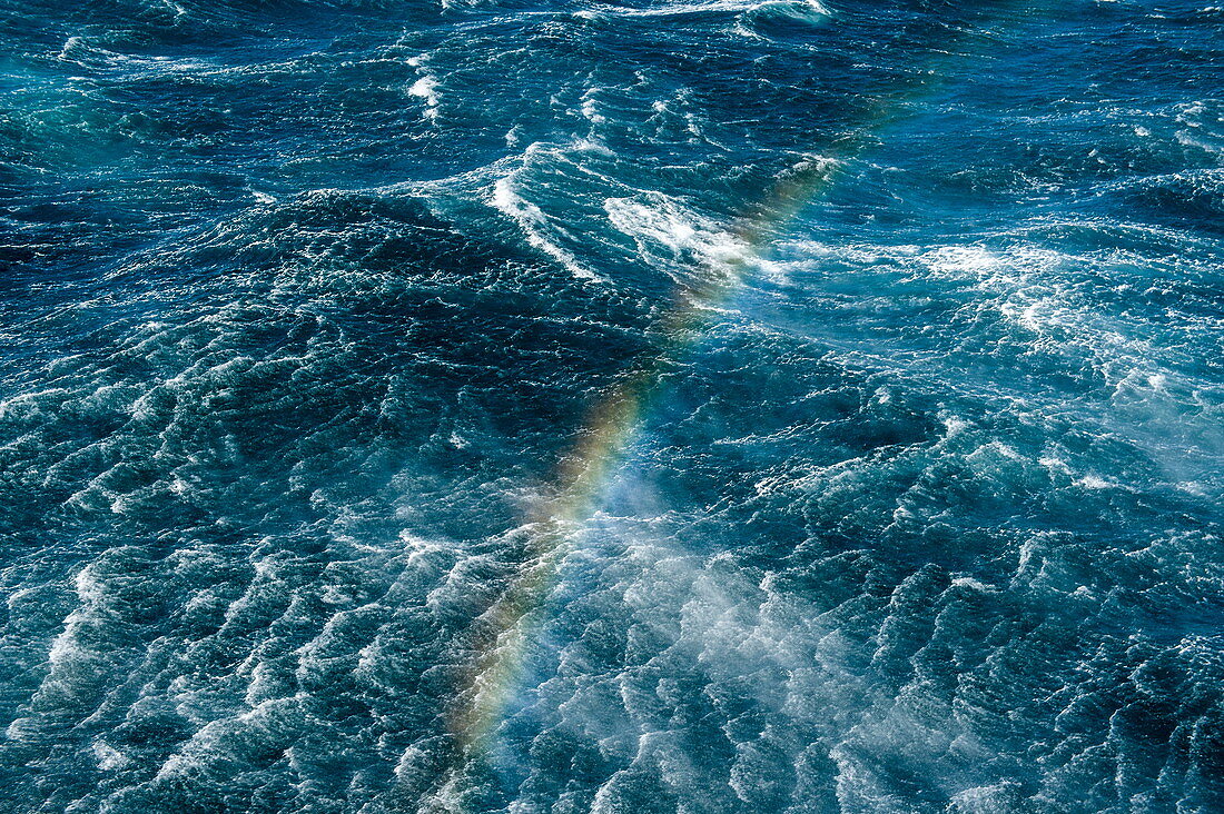 Regenbogen über den Ozeanwellen vom Deck eines Expeditionskreuzfahrtschiffes aus gesehen, nahe Stewart Island, Neuseeland