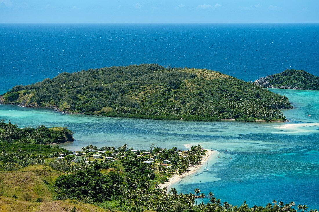 Panoramablick auf kleine Siedlung, zwei Inseln, den Ozean und Riffe in zahlreichen Blau- und Grüntönen, Mamanuca Islands, Fidschi-Inseln, Südpazifik