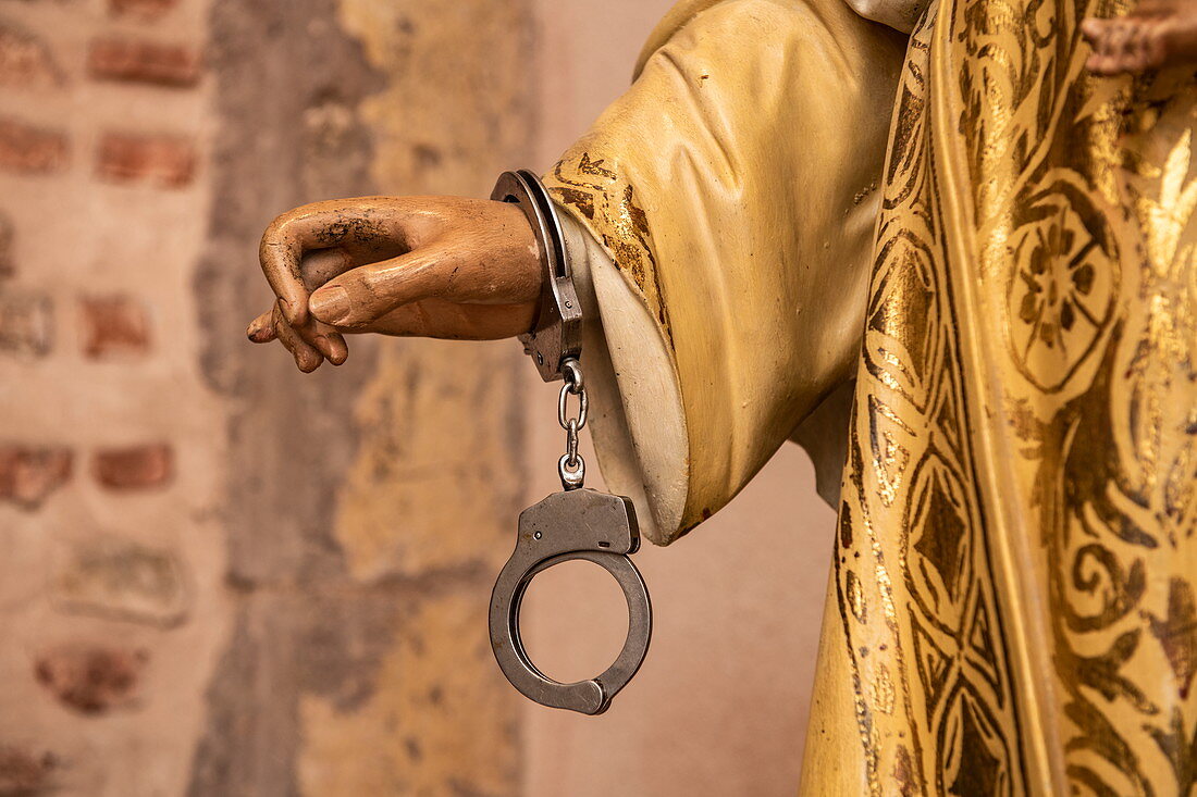 A pair of handcuffs hangs on the wrist of a statue, symbolizing aid to detained believers in Panama City, Panama, Central America