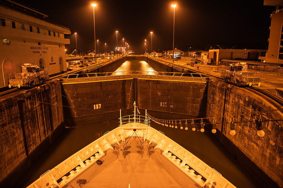 Night view of the bow of an expedition ship in one of the Miraflores locks in the Panama Canal, near Panama City, Panama, Central America