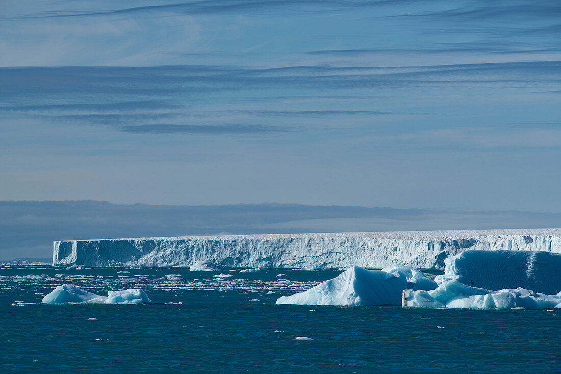 Eine Szene aus losen Eisbergen und der Zunge der Austfonna-Eiskappe unter teilweise bewölktem Himmel, Brasvellbreena, Nordaustlandet, Spitzbergen, Norwegen, Europa