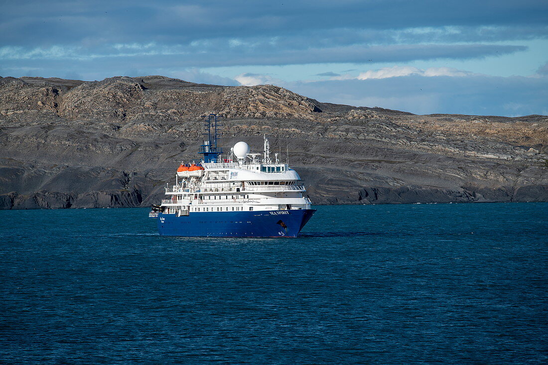 Das Expeditionskreuzfahrtschiff Sea Spirit (Poseidon Expeditions) erwartet die Rückkehr der Passagiere an Land vor dem Hintergrund karger Hügel, Alkhornet, Isfjord, Spitzbergen, Norwegen, Europa