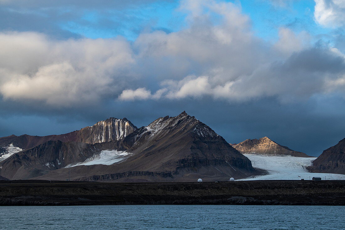 Eine typische Landschaft mit kargen, schroffen mit Schnee bestäubten Bergen und einem sich zurückziehenden Gletscher, Ny-Ålesund, Spitzbergen, Norwegen, Europa