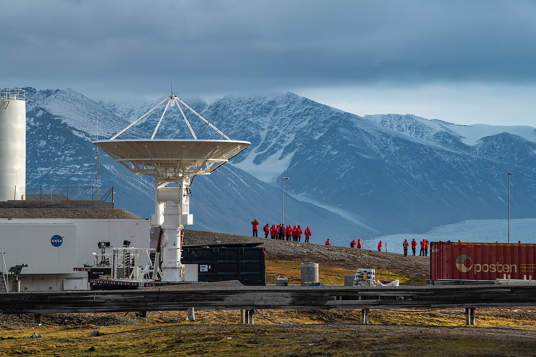 NASA's satellite antenna points to the sky as passengers of the expedition ship Sea Spirit (Poseidon Expeditions) gather for a tour of the research facility, Ny-Ålesund, Spitsbergen, Norway, Europe